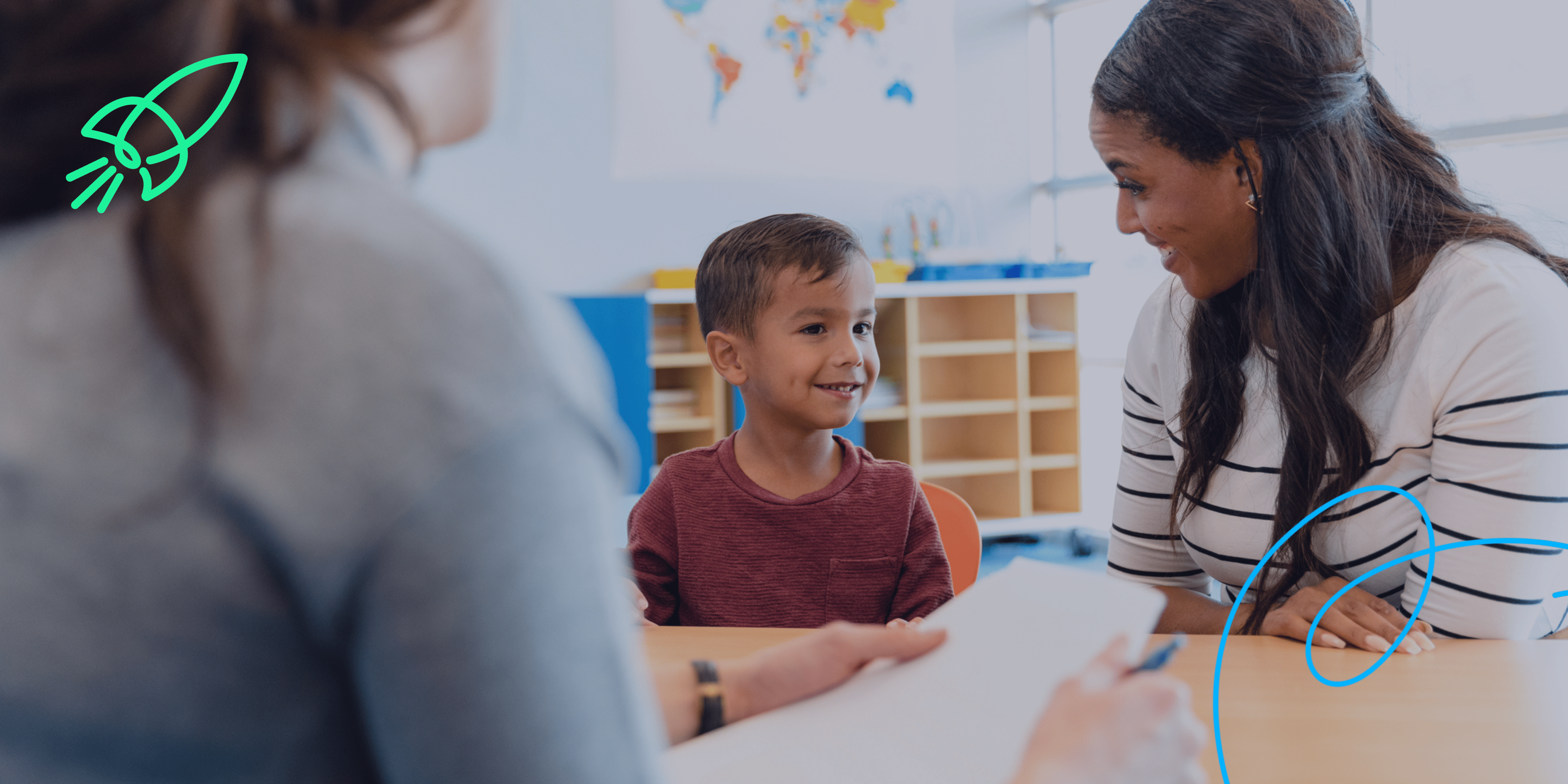 Child smiling in a classroom being supported by a teacher