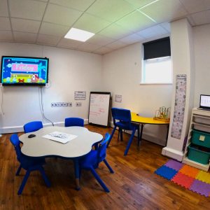 Small classroom space with a TV screen for learning and a whiteboard.